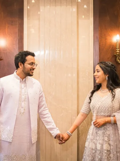 Holding hands in a beautifully lit, elegant indoor space. This shot combines architectural beauty with a simple, romantic gesture.