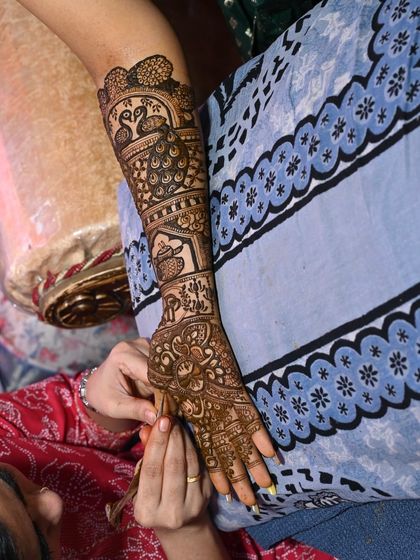 A shot of the mehendi application in progress, showing the arm piece being created.