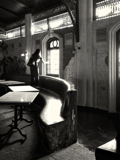 A quiet moment captured in the space, showing a person by the window. The design incorporates natural light to create an inviting daytime atmosphere.