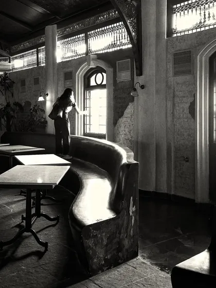 A quiet moment captured in the space, showing a person by the window. The design incorporates natural light to create an inviting daytime atmosphere.