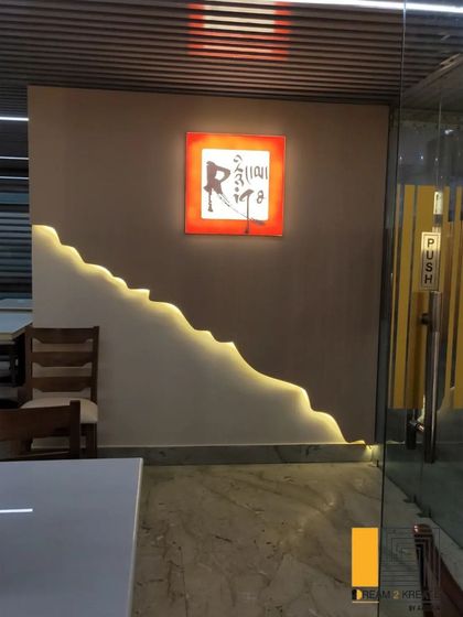 A unique wall feature with integrated lighting that follows an organic, flowing line, adding a custom artistic touch to the restaurant's entrance.