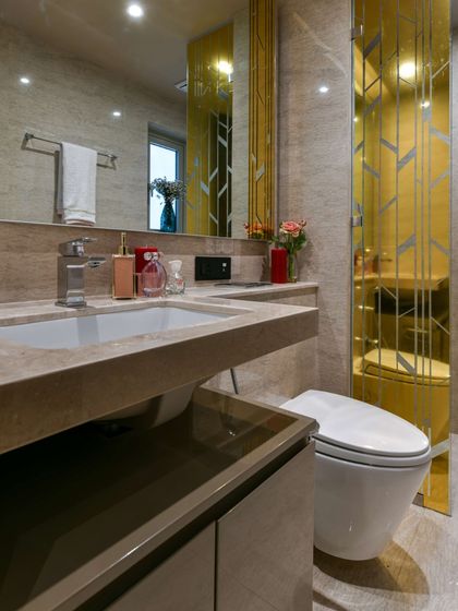 This bathroom is all about clean lines and beautiful finishes. Marble countertops, a gold-framed mirror, and simple lighting create a sleek and sophisticated space for daily routines.