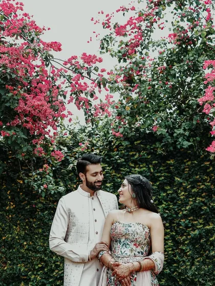 An intimate portrait of the couple surrounded by vibrant pink bougainvillea, creating a romantic and colorful frame.