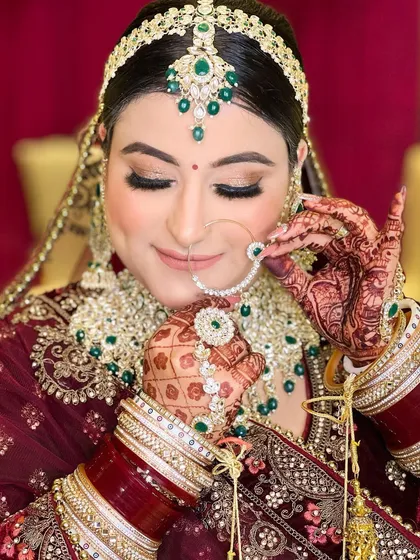A beautiful pose of the same bride adjusting her nose ring, drawing attention to the intricate jewellery and her perfectly manicured hands.