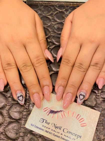 A sweet and simple design on long, nude-pink stiletto nails. The ring fingers are accented with a hand-painted heart filled with a silver glitter pattern.
