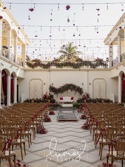 A wide view of a grand courtyard set for a regal wedding. The symmetrical architecture, hanging lights, and elegant seating arrangement create a scene of perfect harmony.