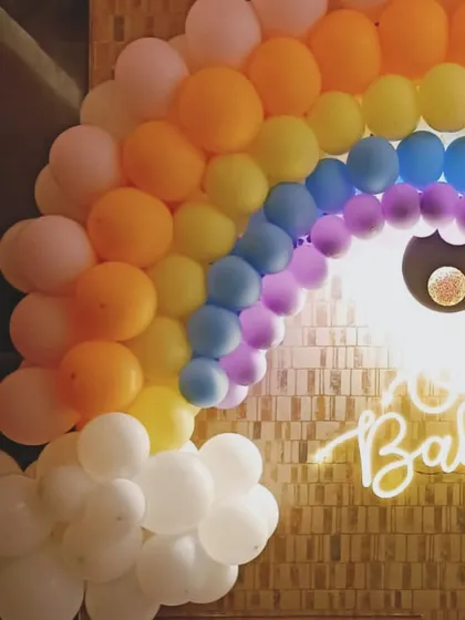 A bright and cheerful rainbow-themed baby shower. The balloon rainbow arch and "Oh Baby" neon sign create a joyful and optimistic atmosphere.