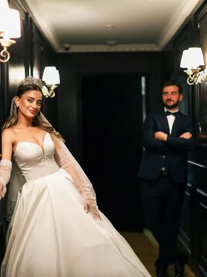 A stylish pose in a hotel corridor. The bride takes center stage while the groom stands in the background, creating a modern and fashionable wedding portrait.