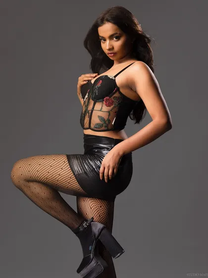 A three-quarter shot of a model in an embroidered corset and leather skirt. The pose is confident and strong, perfect for a fashion editorial.