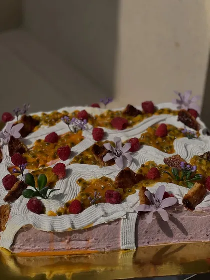 The beautiful, wavy frosting on our passion fruit raspberry sheet cake, decorated with fresh raspberries and edible flowers. It looks as good as it tastes.