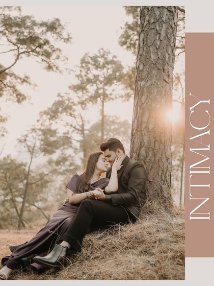 A deeply romantic shot of a couple nestled at the base of a tree, the word 'Intimacy' beautifully overlaid, capturing a quiet moment of connection in nature.