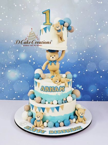 An adorable teddy bear-themed cake for Arham's first birthday. This three-tier creation features a gravity-defying top tier held up by a cute bear.