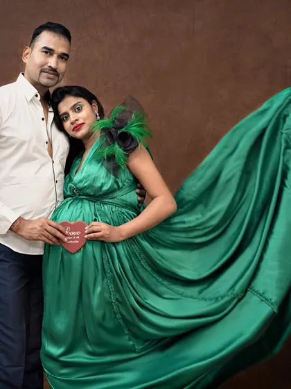 The flowing green fabric creates a beautiful sense of movement in this shot. The couple holds a small heart, a sweet symbol of the new love they are about to welcome.