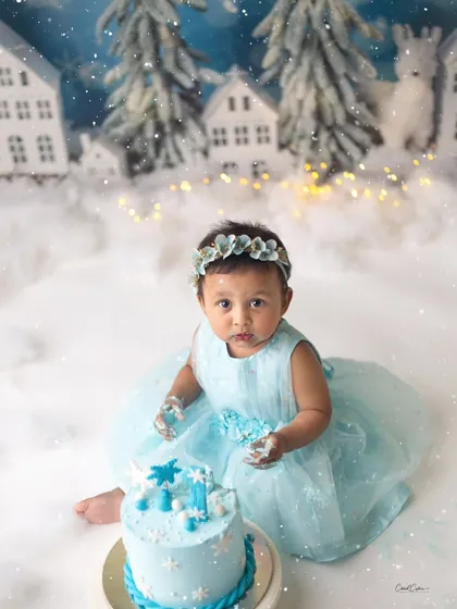 A moment of curiosity before the fun begins. This little one is taking a good look at her winter-themed cake, ready to make a mess.