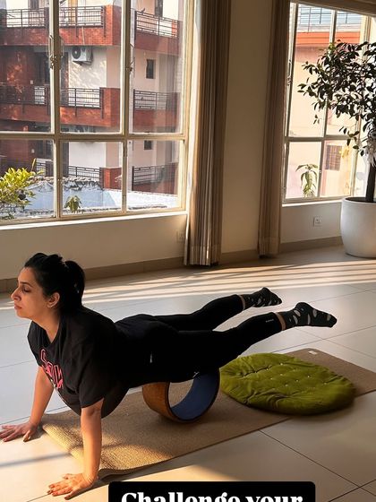 A student demonstrates a challenging balance pose on the yoga wheel, showcasing the strength and focus cultivated in our classes.