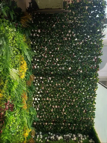 This balcony corner uses a mix of artificial foliage panels and a bed of white pebbles for a clean, zen-inspired look.