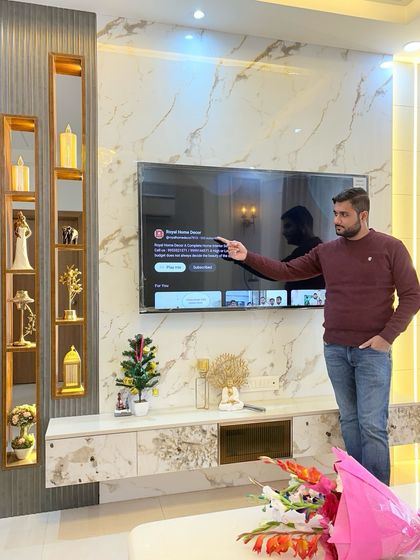 Pointing out the details of the TV unit, with the open kitchen visible in the reflection and background.