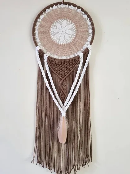 Where rustic meets ethereal. This earth-toned macrame dreamcatcher weaves dreams into reality, capturing the essence of nature's embrace with its brown and white tones.