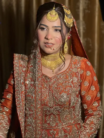 The traditional jewelry and rich color of her outfit are perfectly complemented by the soft, glamorous makeup. This is a modern take on a classic Nikah look.