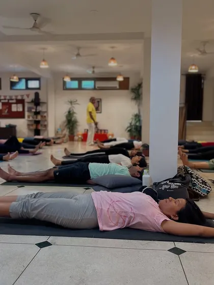 A class rests in Savasana after a vigorous asana practice. This final relaxation is essential for integrating the benefits of the poses and allowing the body to enter a state of deep healing.