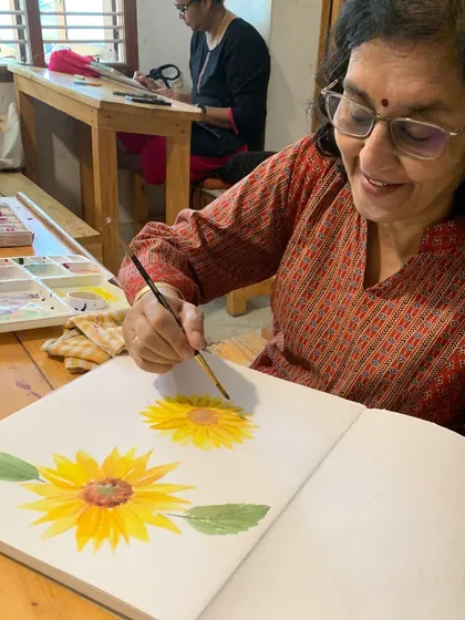 A student's joy is as radiant as the sunflower she is painting. Art has a wonderful way of reflecting the artist's own warmth and creativity.