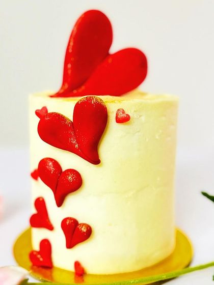 A lovely white mini cake decorated with a cascade of red hearts. The design is playful and romantic, perfect for celebrating love on Valentine's Day or an anniversary.