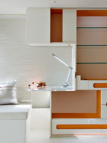 This bespoke haven, 'The Cocoon,' was meticulously crafted for a couple, featuring a futuristic yet organic design. The space-saving, modular unit combines a desk and shelving with a pop of orange, embodying our approach to fluid design and clutter-free environments.