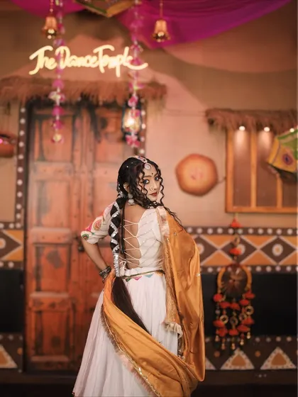 A back shot from the 'Gori Radha' performance, highlighting the beautiful blouse design and hairstyle, with The Dance Temple's neon sign in the background.