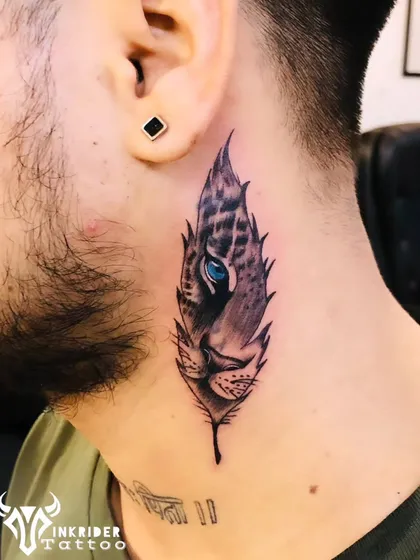 This piece cleverly combines a tiger's eye with a feather design to cover an old tattoo on the neck. The striking blue eye provides a focal point, while the detailed line work and shading ensure the old ink is no longer visible.