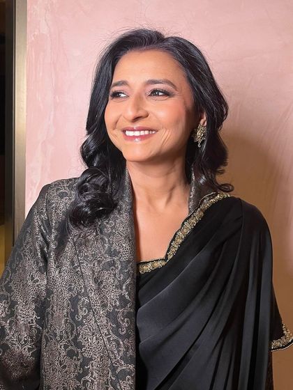 A candid moment of happiness. Her makeup is natural and glowing, perfect for celebrating her child's wedding day.