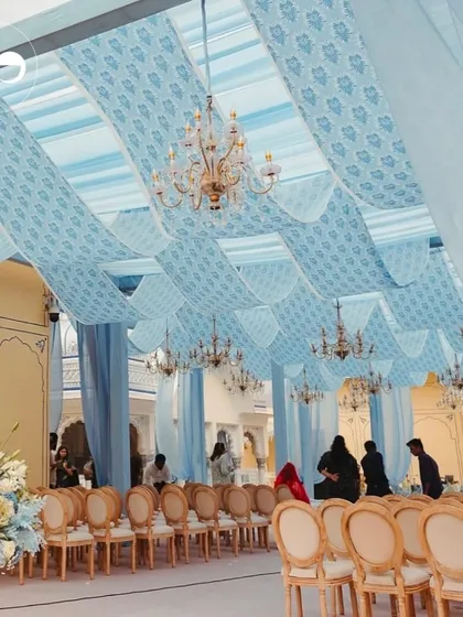 An alternate view of the Jaipur-blue themed event, showcasing the flowing, patterned ceiling drapes and elegant chandeliers. This combination of traditional prints and classic fixtures created a truly unique and luxurious space.