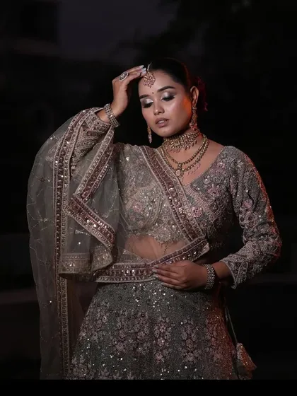 A graceful, artistic pose showing the delicate dupatta and blouse work of the grey and pink lehenga.