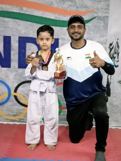 Posing with another young champion from the DTSA team. He is holding his medal and trophy with pride after a great performance.