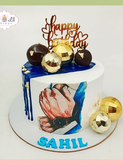 A stylish birthday cake for Sahil, featuring a hand-painted design and a cascade of gold and blue disco ball spheres.