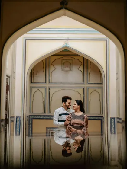 A creative reflection shot taken at a palace in Jaipur. The water on the ground creates a perfect mirror image, adding a unique and artistic element to this couple portrait.