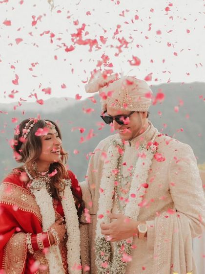 A joyous moment captured. The groom wears our custom-designed sherwani, paired with a matching safa and sunglasses for a cool, modern twist on a classic wedding look.