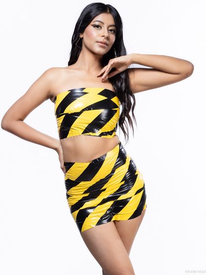 A confident studio portrait in a unique, caution tape-inspired two-piece. This is an example of a conceptual fashion shoot with a bold, graphic look.