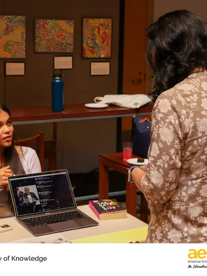 A student uses her laptop to supplement her TOK presentation, integrating digital media with physical objects to explore how knowledge is constructed. This reflects our modern approach to learning and inquiry.