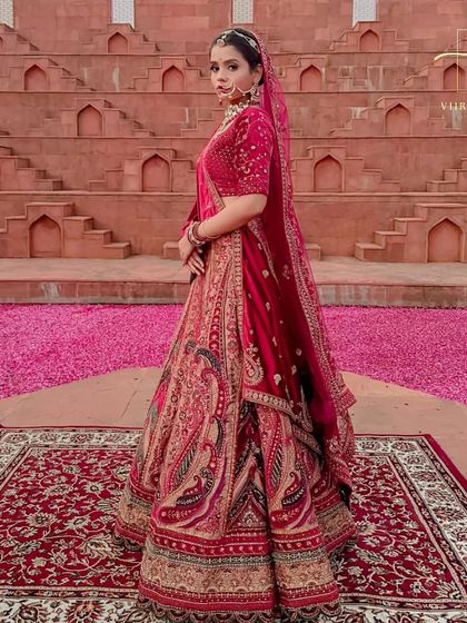 A side view of the red bridal lehenga, showing the beautiful fall of the skirt and the detailed border work.