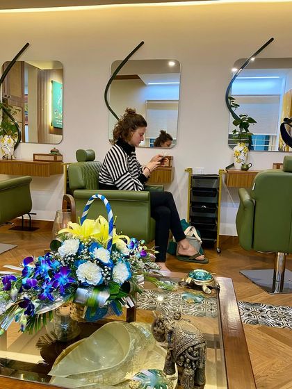 A wide shot of the salon, capturing the blend of comfortable seating, elegant decor, and a relaxed client.