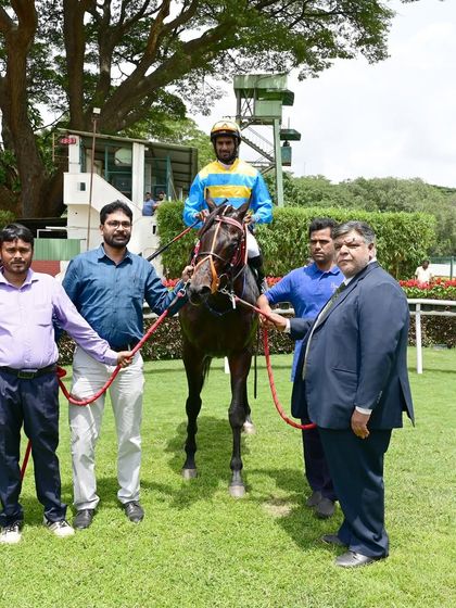 Tolkien stands in the winner's enclosure after securing The Champion Trainer Cup, alongside jockey S. Antony Raj and the owners.
