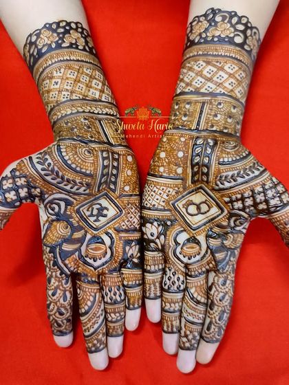 A beautiful example of a traditional engagement mehendi. The design incorporates the couple's initials and ring symbols within a dense pattern of peacocks, florals, and classic checkwork.