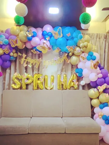A colorful butterfly-themed balloon garland in pastel shades. This organic arch is designed to frame a sofa, creating a perfect spot for photos during the birthday party.