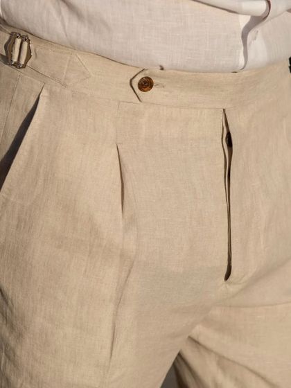 Our linen trousers feature elegant details like front pleats and a buckled side adjuster, combining classic tailoring with the relaxed feel of linen.