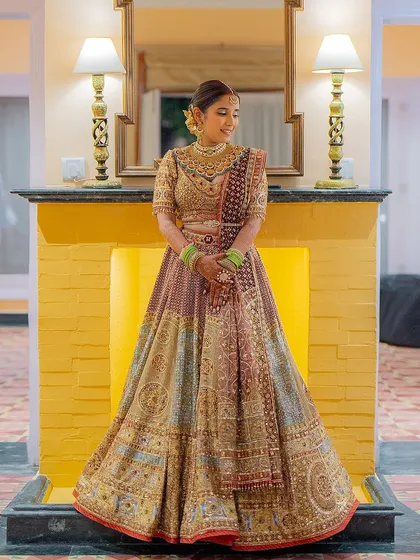 A full-length portrait of the bride in her multi-toned Tarun Tahiliani reception lehenga. The rich colors and intricate details create a look of regal elegance.