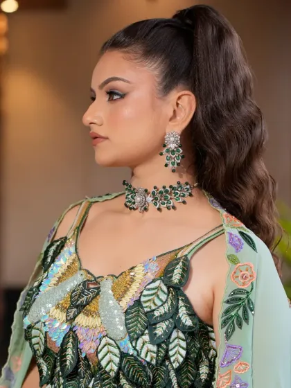 Another angle of the pastel green lehenga, focusing on the intricate, nature-inspired blouse and the matching emerald green jewellery set.