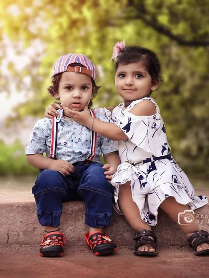 An adorable outdoor portrait of a brother and sister. The gentle interaction as she touches his chin makes for a truly special and authentic sibling photograph.