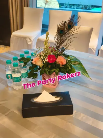 A table setting for a Teej party, featuring a floral centerpiece with peacock feathers, showing our attention to every detail.