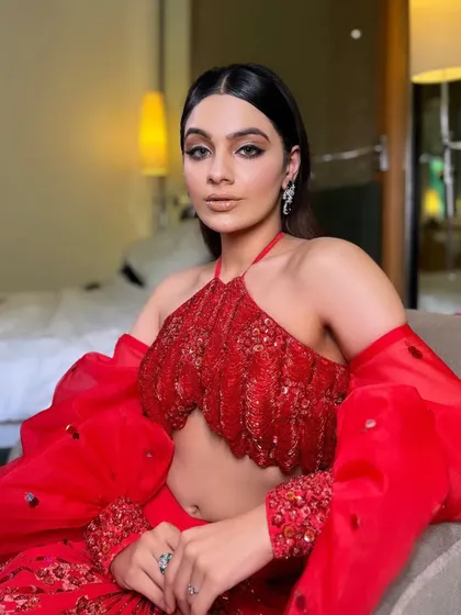 "Presenting a perfect Glam." This indoor shot showcases the intricate beadwork on the red halter top, a key detail of this sunset gala look.