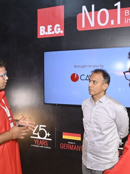 An exhibitor for B.E.G., a German brand, discusses sensor technology with attendees, demonstrating the expo's role in bringing global brands to the Indian market.